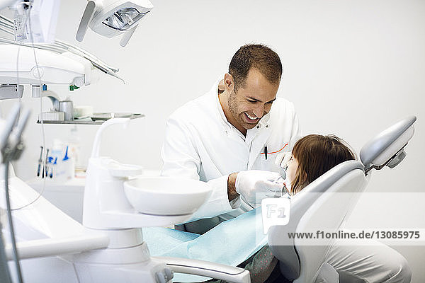 Lächelnder Zahnarzt untersucht die Zähne von Mädchen in der Klinik