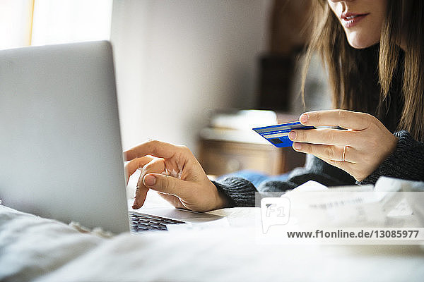 Ausgeschnittenes Bild einer Frau  die zu Hause mit Kreditkarte online einkauft
