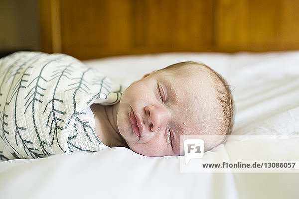 Close-up of baby boy sleeping on bed at home