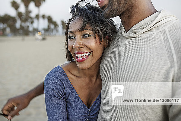 Glückliche Frau umarmt Mann am Strand