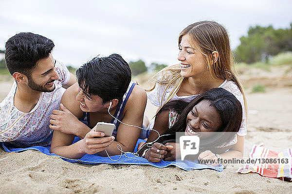 Verspielte multi-ethnische Freunde am Strand