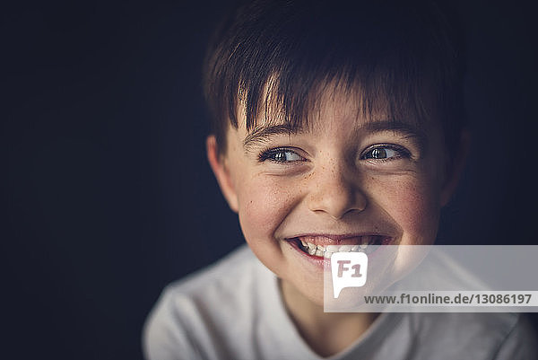 Fröhlicher Junge mit Zahnlücke schaut in der Dunkelkammer weg