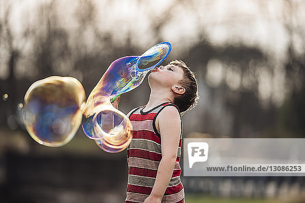 Junge bläst Blasen beim Spielen im Park