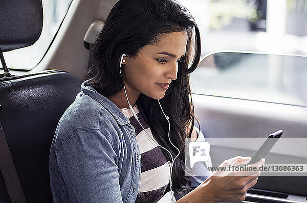Junge Frau schreibt im Taxi SMS