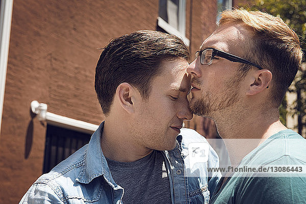Gay couple embracing while standing outside house