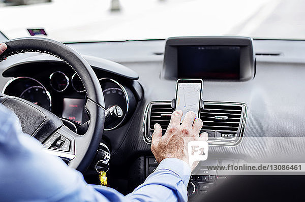 Ausgeschnittenes Bild eines Geschäftsmannes mit GPS auf einem Smartphone im Auto