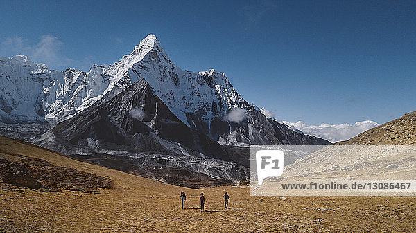 Rückansicht von Wanderern  die die Landschaft gegen den blauen Himmel im Sagarmatha-Nationalpark durchwandern