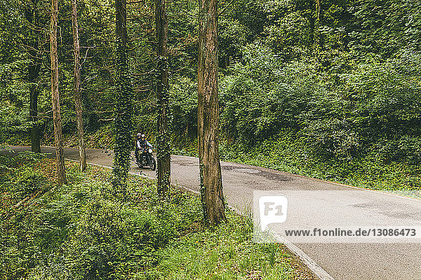 Paar fährt Motorrad auf Straße im Wald