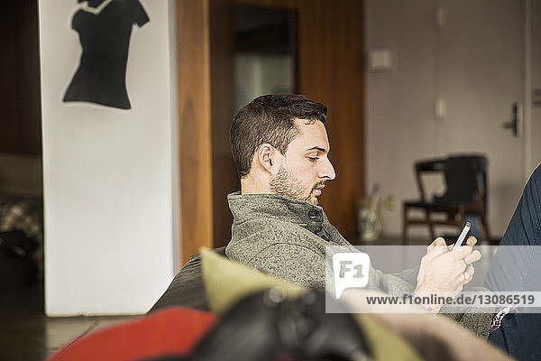 Seitenansicht eines Geschäftsmannes  der telefoniert  während er im Kreativbüro auf dem Sofa sitzt