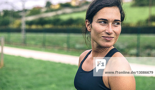 Nachdenkliche Frau schaut weg  während sie im Park Sport treibt