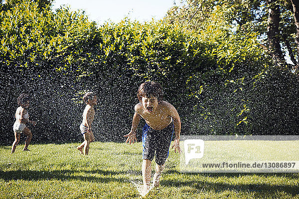 Zwei Jungen spielen im Sprinkler
