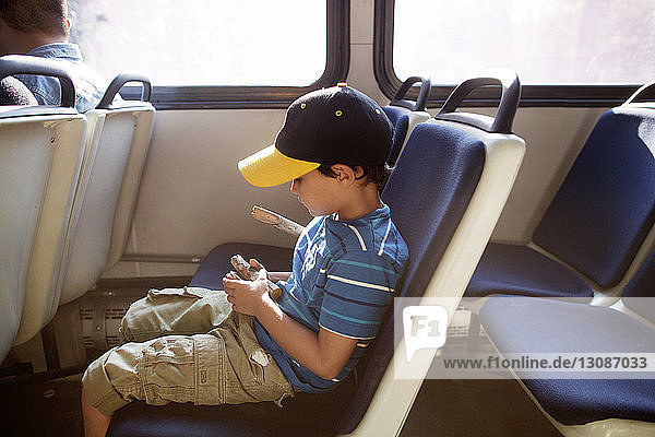 Boy holding wood and sitting on seat while travelling in train