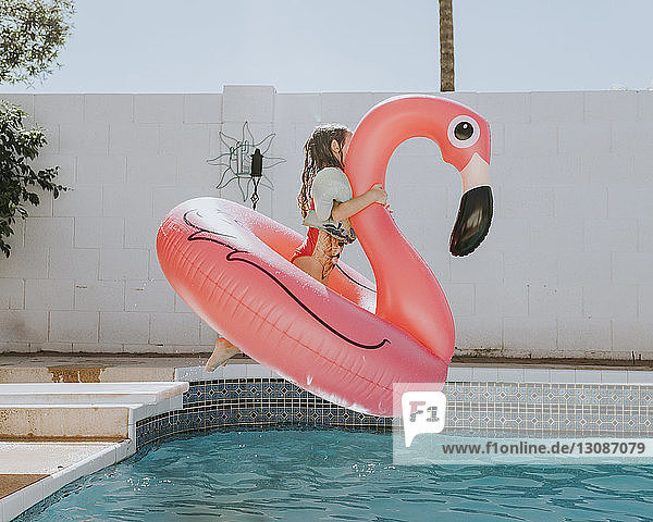 Mädchen springt mit Gummiente im Schwimmbad