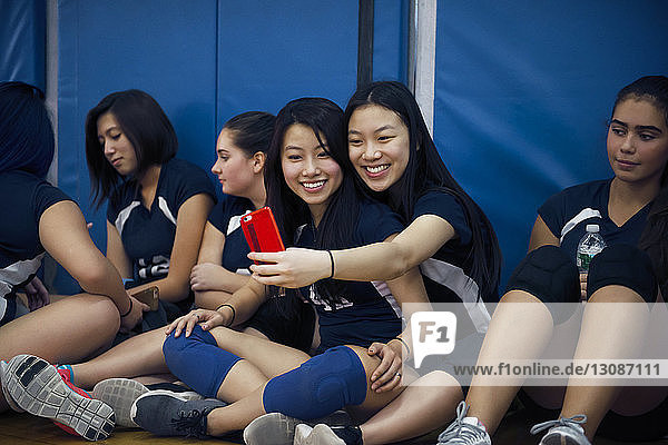 Teenager-Mädchen klicken beim Entspannen auf dem Volleyballfeld auf Selfie