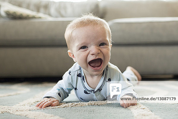 Porträt eines fröhlichen kleinen Jungen  der zu Hause auf einem Teppich liegt