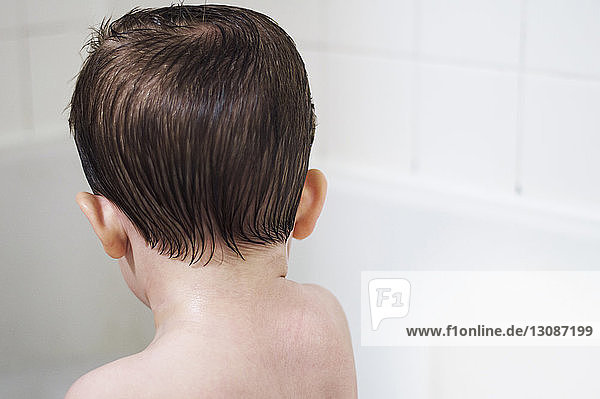 Rückansicht eines Jungen ohne Hemd in der Badewanne zu Hause
