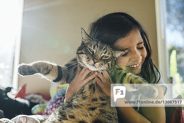Glückliches Mädchen mit Katze im Bett zu Hause