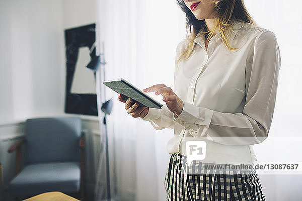 Midsection of businesswoman using tablet computer in office