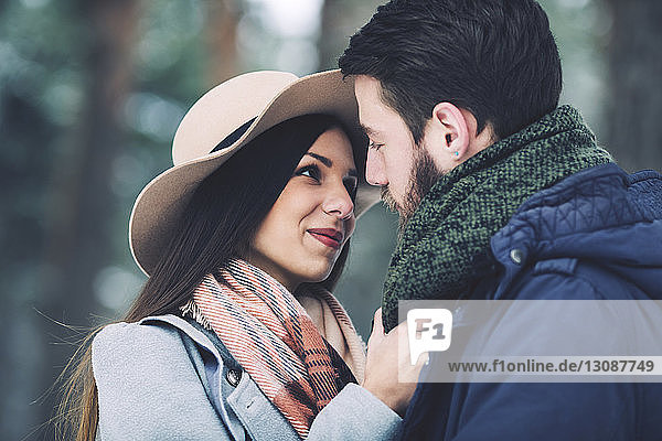 Close-up of romantic couple looking at each other in forest during winter