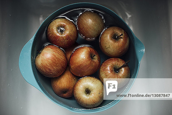 Draufsicht auf Äpfel mit Wasser in einer Schüssel auf der Küchenspüle