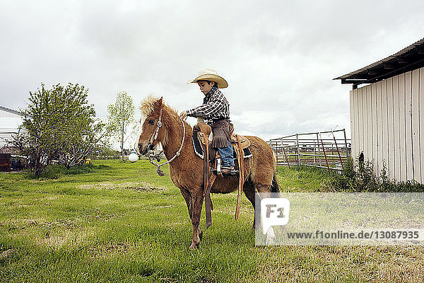 Cute cowboy riding horse on ranch
