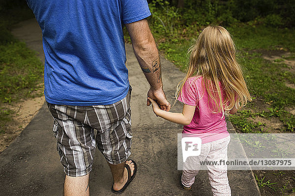 Niedrigerer Abschnitt eines Mannes  der mit seiner Tochter auf einem Fußweg geht