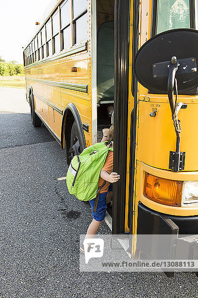 Boy getting in school bus on street