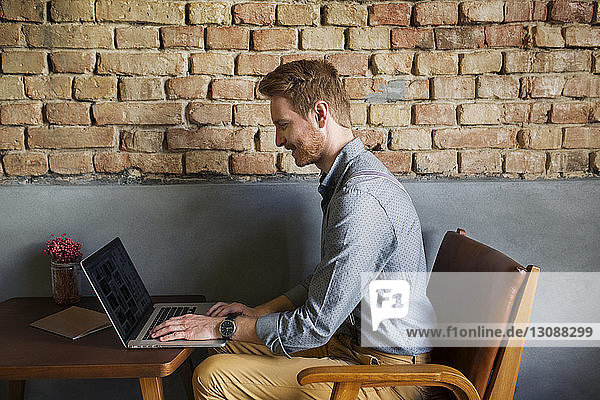 Seitenansicht eines kreativen Geschäftsmannes mit Laptop in der Hotellobby