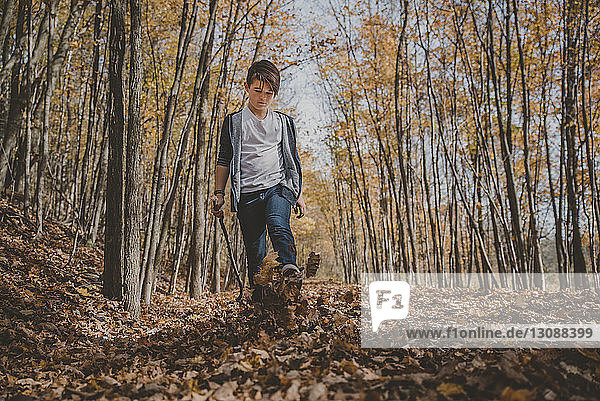 Full length of boy kicking leaves on field during autumn