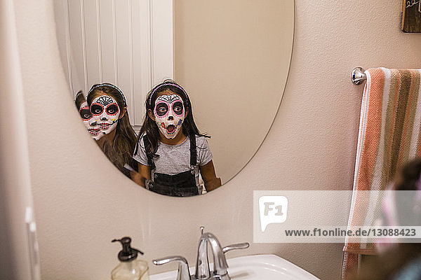 Sisters with face paint looking into mirror
