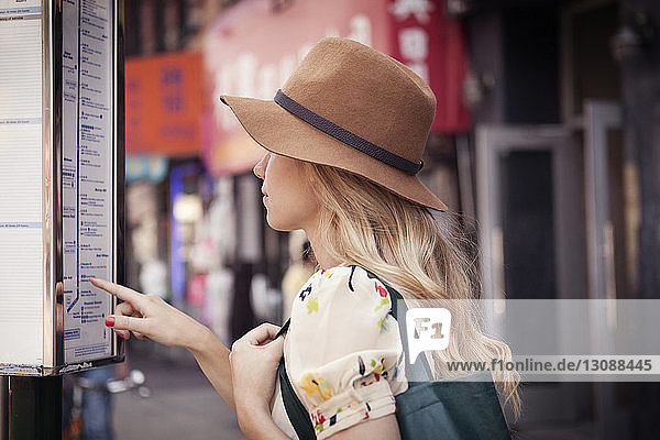 Frau mit Hut liest Karte in der Stadt