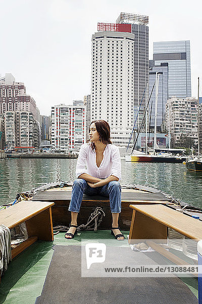 Weibliche Touristin sitzt in Hongkong auf einem Boot vor Gebäuden