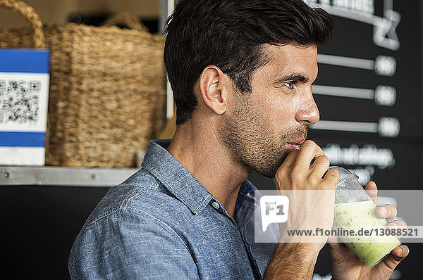 Side view of man drinking smoothie while standing by food truck