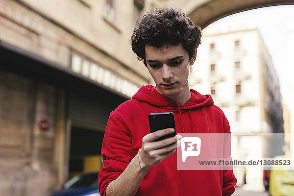 Teenage boy using smart phone in city