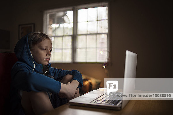 Junge benutzt Laptop-Computer auf dem Tisch  während er zu Hause sitzt