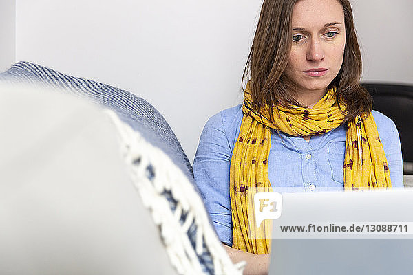Niedriger Blickwinkel einer Frau  die einen Laptop-Computer benutzt  während sie auf dem Sofa im Wohnzimmer sitzt