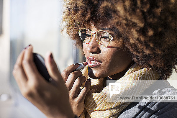 Close-up of woman applying lipstick at bus stop