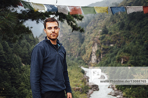Porträt eines Wanderers  der am Fluss inmitten der Berge im Sagarmatha-Nationalpark steht
