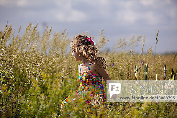 Glückliches Mädchen geht inmitten von Pflanzen auf Grasfeld