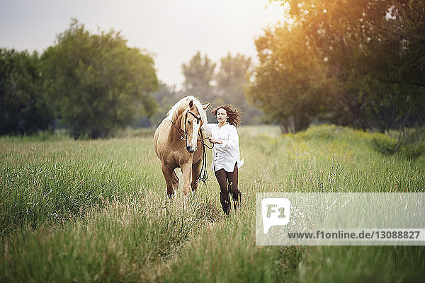 Mid adult woman and horse running on grassy field at countryside