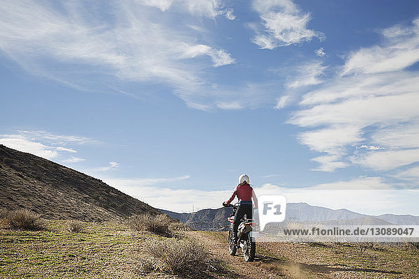 Rear view of woman riding motorcycle on mountain against sky