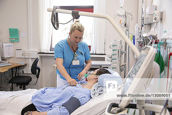 Female doctor examining patient lying on bed in hospital