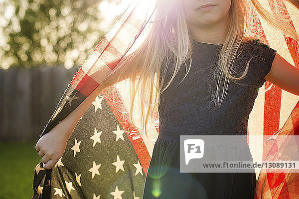 Midsection of girl with American flag in backyard