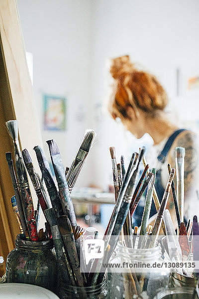 Nahaufnahme von Pinseln mit Künstler im Hintergrund im Atelier