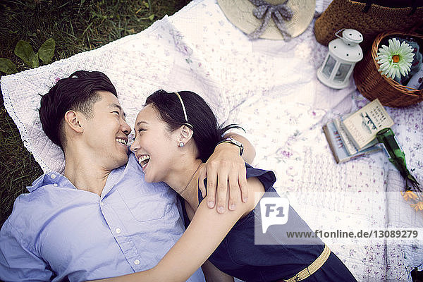 Overhead view of happy couple lying on field at park