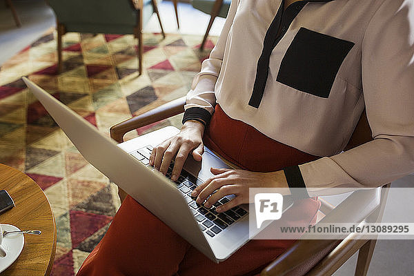 Mittelsektion einer Geschäftsfrau mit Laptop in der Hotellobby