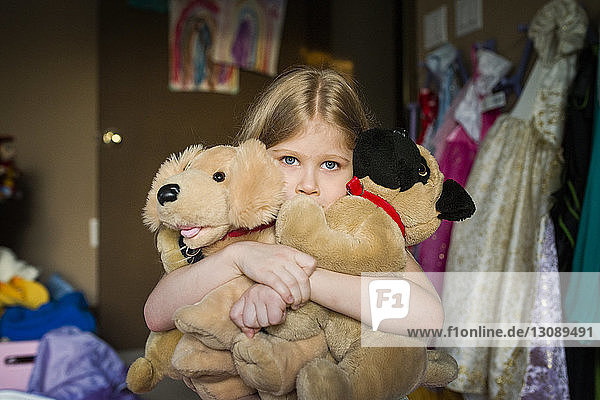 Girl holding stuffed toys in bedroom at home