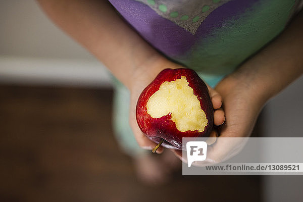 Low section of girl holding eaten apple at home