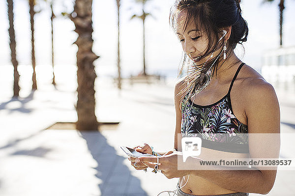 Sportliche Frau hört im Sommer auf Wanderwegen Musik über Smartphone