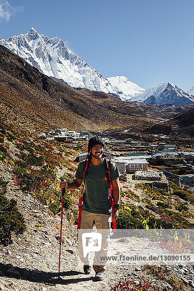 Male hiker with hiking pole walking on mountain against blue sky at Sagarmatha National Park